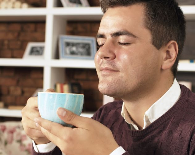 man with eyes closed holding a cup of tea
