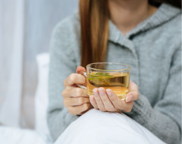 woman holding a clear mug of thca tea